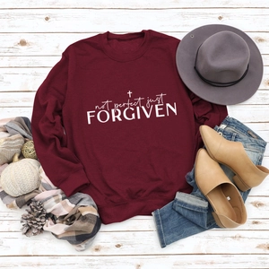 Close-up of wine red sweatshirt with Not Perfect Just Forgiven slogan and cross print