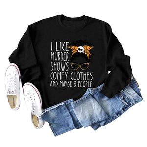 Flat lay of black crewneck sweatshirt with 'I LIKE MURDER SHOWS' text and cartoon graphic