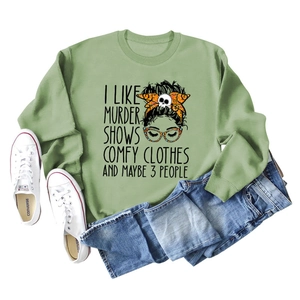 Flat lay of green crewneck sweatshirt with 'I LIKE MURDER SHOWS' graphic and jeans