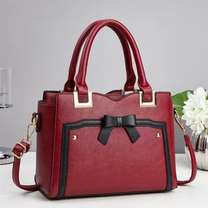 Close-up of red lychee texture handbag with black bow detail and gold hardware