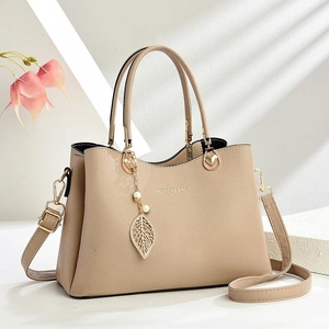 Detail of apricot pebbled leather handbag with gold leaf and pearl charm decoration
