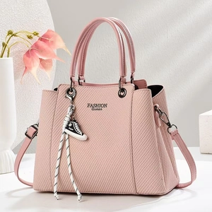 Detail of pink woven texture handbag with FASHION Queen logo and mini sneaker charm