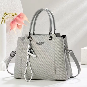 Detail view of grey textured leather tote with Fashion Queen print and sneaker charm