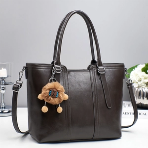 Chic dark brown faux leather tote bag with plush lion charm and adjustable shoulder strap