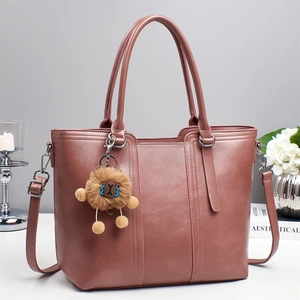 Detail view of large mauve leather tote bag with reinforced handles and plush charm
