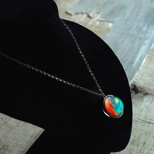 Cosmos galaxy double-sided glass ball pendant necklace on a black jewelry display stand