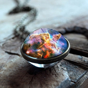 Close-up of galaxy nebula glass sphere pendant with antique bronze chain on wood