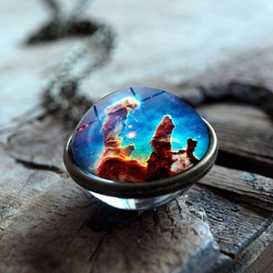 Detailed view of galaxy nebula glass dome pendant necklace on vintage wooden background