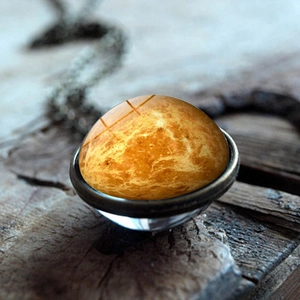 Κοντινό πλάνο γυάλινου μενταγιόν με υφή πλανήτη σε ρουστίκ ξύλινο φόντο