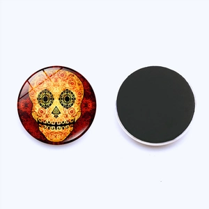 Détail d'un aimant de réfrigérateur rond en verre avec motif de crâne en sucre mexicain et dos