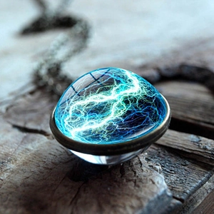 Macro shot of glass dome necklace with blue lightning patterns on a rustic wood background