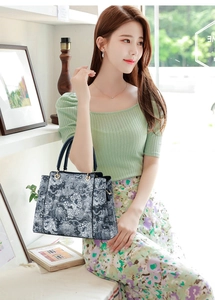 Détail macro du motif floral gaufré sur sac cabas bleu avec anneaux métalliques