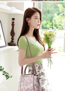 Détail du sac brodé de fleurs avec un haut en tricot vert et une jupe à fleurs élégante