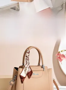 Detail of beige textured leather tote with silk scarf handle and metal logo accent