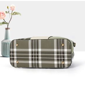 Detailed base of green plaid handbag featuring four gold metal protective studs