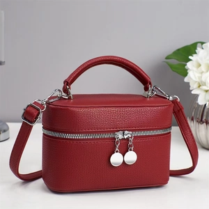 Detail view of red lychee pattern handbag with silver zippers and adjustable strap