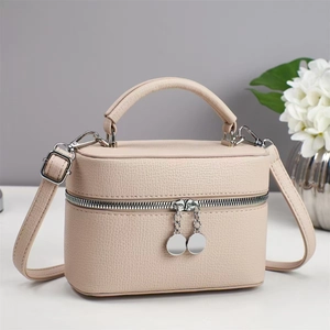 Detail of beige lychee pattern texture and silver zipper on cylindrical crossbody bag