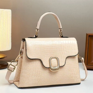 Elegant cream crocodile-embossed handbag with gold hardware and adjustable strap