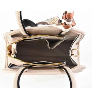 Top view of beige leather handbag interior showing main compartment and zippered side pocket