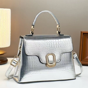 Detailed close-up of silver crocodile embossed handbag with luxury gold twist lock