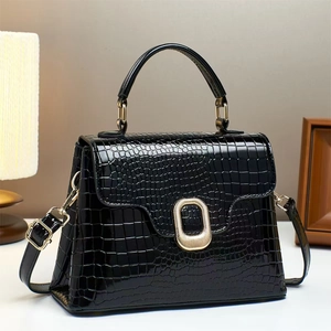 Detailed view of black crocodile pattern leather handbag with gold metallic buckle