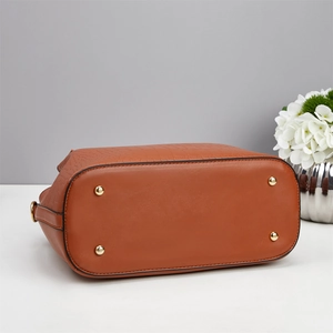 Detail view of the brown crocodile pattern handbag base with four golden protective studs