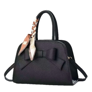 Minimalist black bow handbag with vintage leather texture and decorative printed silk scarf