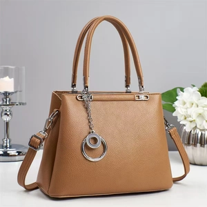 Detail view of camel lychee leather texture and silver chain charm on the tote bag