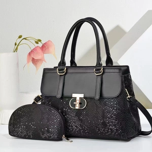 Detail of black faux crocodile leather tote bag set with golden metal hardware and strap