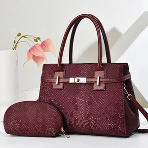 Detailed macro view of wine red snakeskin texture and gold metal buckle on a tote bag
