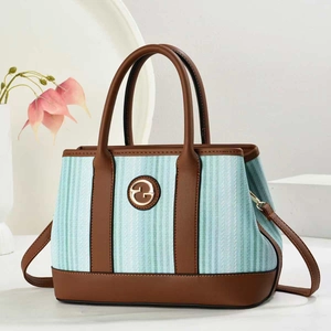 Détail du sac cabas en toile rayée bleue et blanche avec poignées en cuir marron et logo