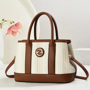 Détail du sac cabas en toile rayée avec garniture en cuir marron et logo métallique