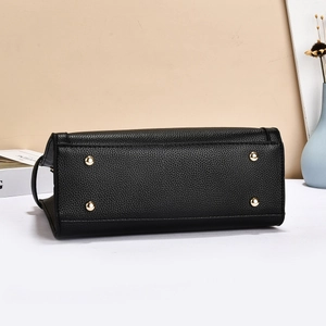 Détail du fond d'un sac à main en cuir noir avec quatre pieds de protection en métal doré