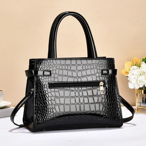 Detailed view of black crocodile pattern leather handbag with gold zipper and dual handles