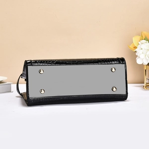 Detail view of the black crocodile pattern handbag bottom with four gold metal protective studs