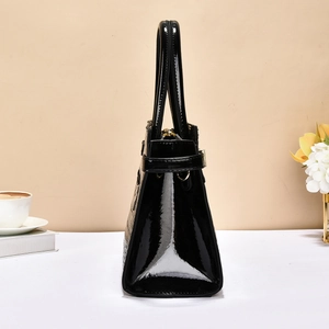 Side view of black crocodile pattern patent leather handbag with polished metal details