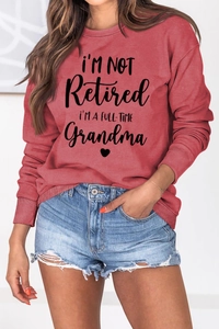 Detail of brick red sweatshirt with grandma slogan and ribbed cuffs on female model