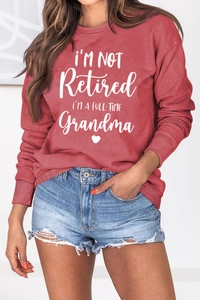 Close-up of ribbed cuffs and white letter print on a dark red crewneck sweatshirt
