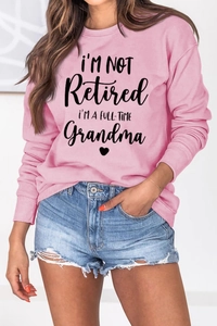 Detailed view of pink sweatshirt with I'm Not Retired I'm A Full-Time Grandma print