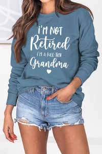 Detail of greyish-blue cotton sweatshirt featuring white script grandma slogan and heart