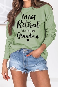 Detail of mint green sweatshirt featuring black I'M NOT Retired Grandma letter print