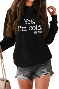 Detail of white Yes I'm Cold 24:7 text printed on black oversized hoodie fabric