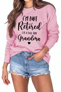 Close-up of pink long sleeve sweatshirt featuring black printed grandma slogan and heart