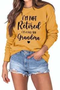 Detail of loose mustard yellow sweatshirt with full-time grandma slogan and heart pattern