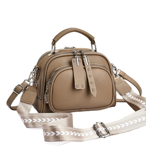 Brown leather crossbody bag with triple zipper compartments and woven shoulder strap