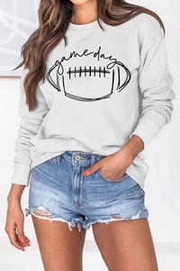 Détail du graphique Game Day sur sweatshirt blanc avec un short en jean effiloché
