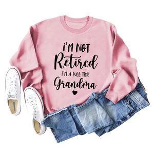 Detailed view of pink cotton sweatshirt featuring grandma slogan print with denim jeans