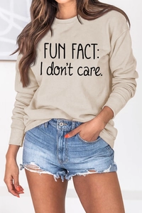 Detail of Fun Fact I Don't Care slogan print on beige crewneck sweatshirt and denim shorts