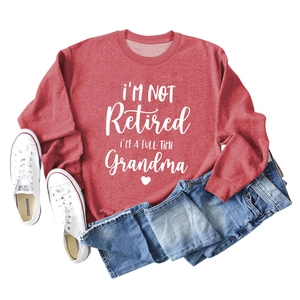 Flat lay of red crewneck sweatshirt featuring white grandma slogan with denim jeans