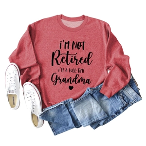 Flat lay of a red long sleeve sweatshirt featuring a funny Grandma slogan and denim jeans